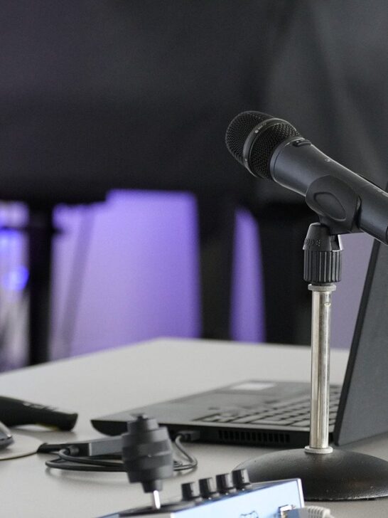 Set up for a podcast including laptop and microphone with sound[proof curtain in the background