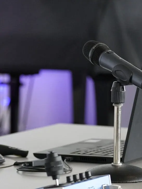 Set up for a podcast including laptop and microphone with sound[proof curtain in the background