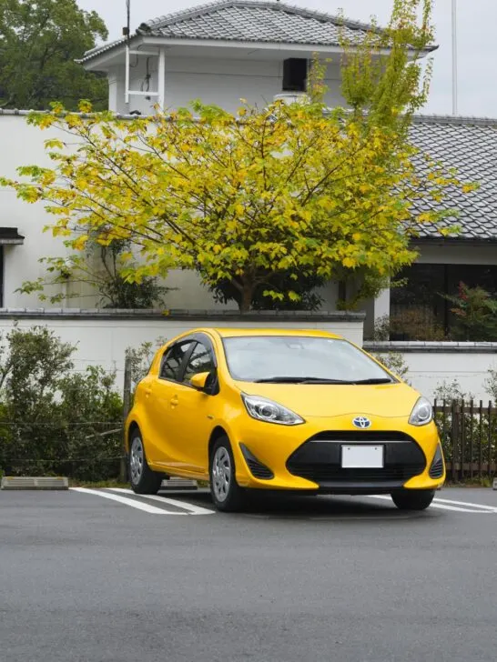 A yellow Prius, one of the first hybrid vehicles , parked front end out