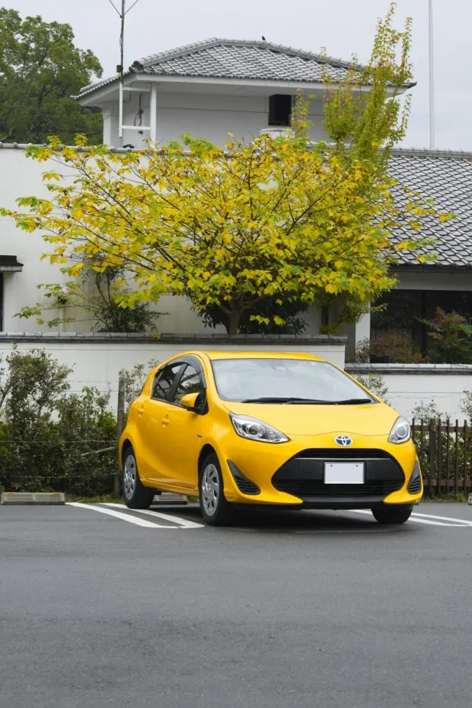 A yellow Prius, one of the first hybrid vehicles , parked front end out