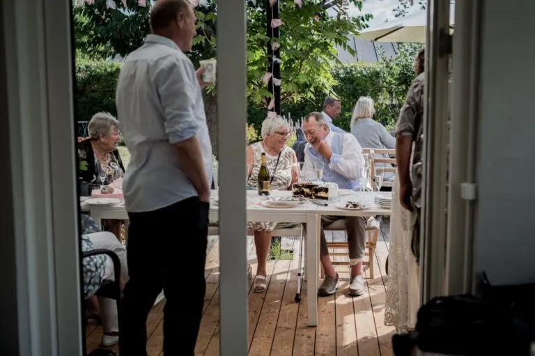 a group of people outside eating on the back deck of a home whilehosting the ultimate gathering