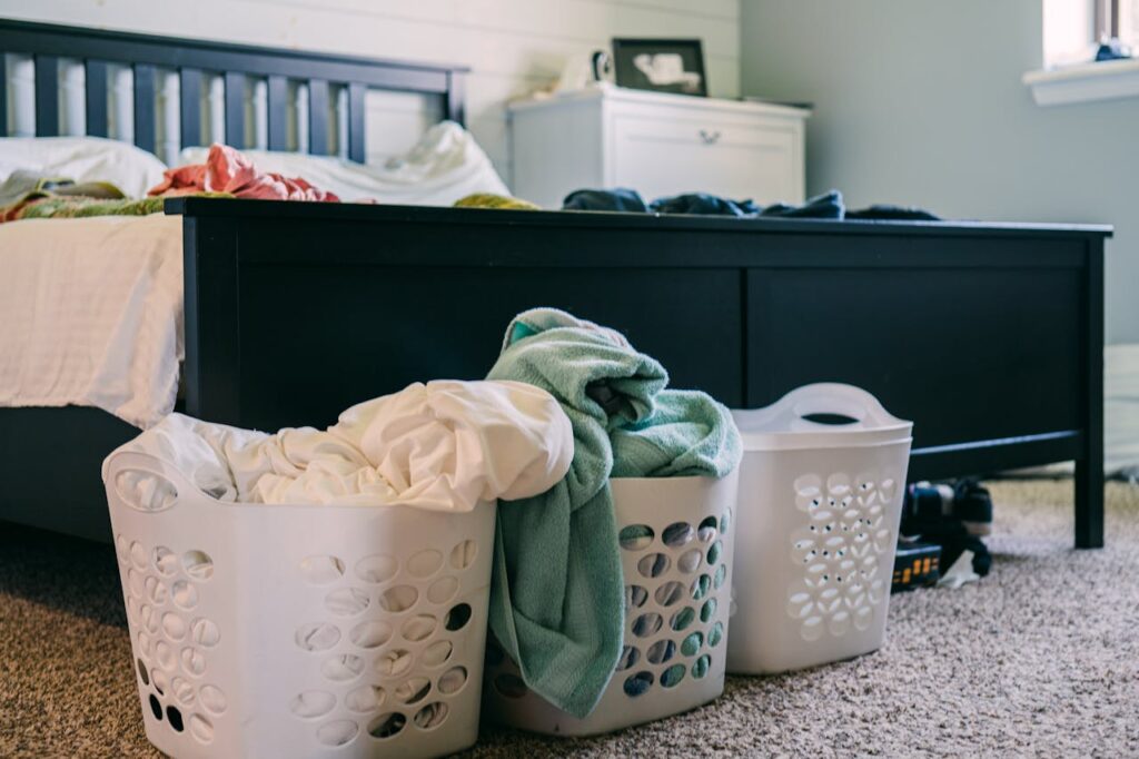 Three laundry hampers for clothes at the end of a bed