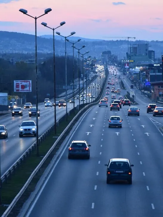 Cars driving on a highway at sunset using vehicle tracking devices
