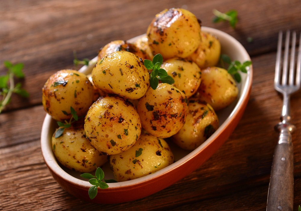 Delicious roasted young potatoes in bowl - stock image