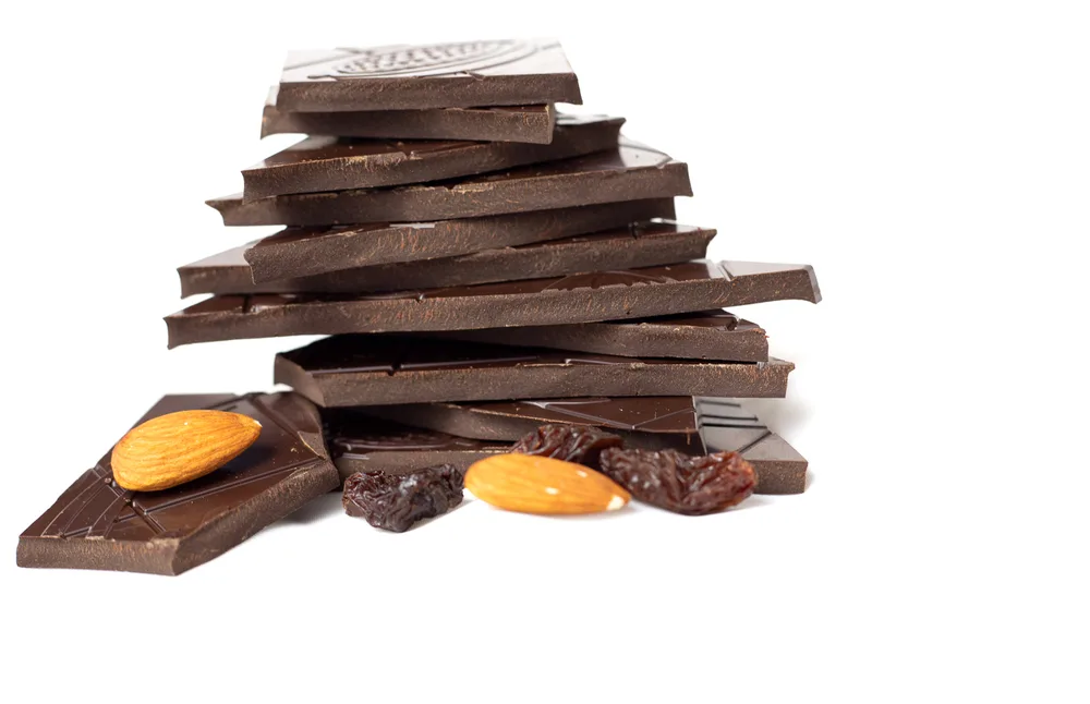 Closeup Pieces Dark Inferior Chocolate Almonds Raisins White Background — Stock Photo, Image