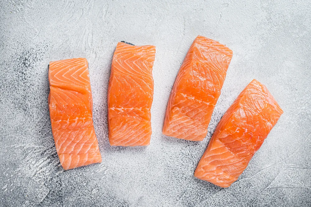 Raw salmon fillet steak on kitchen table. White background. Top view.
