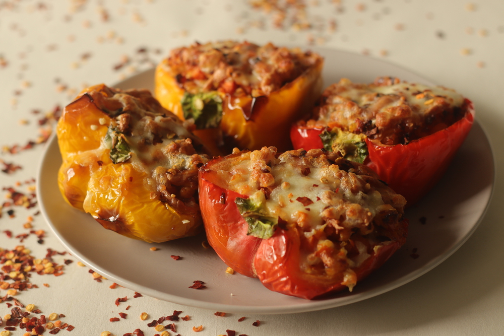 Stuffed bell peppers. Made by air frying the Bell peppers stuffed with a spicy mixture of sauteed cottage cheese and carrots, sprinkled with mozzarella cheese on top. Shot on white background.