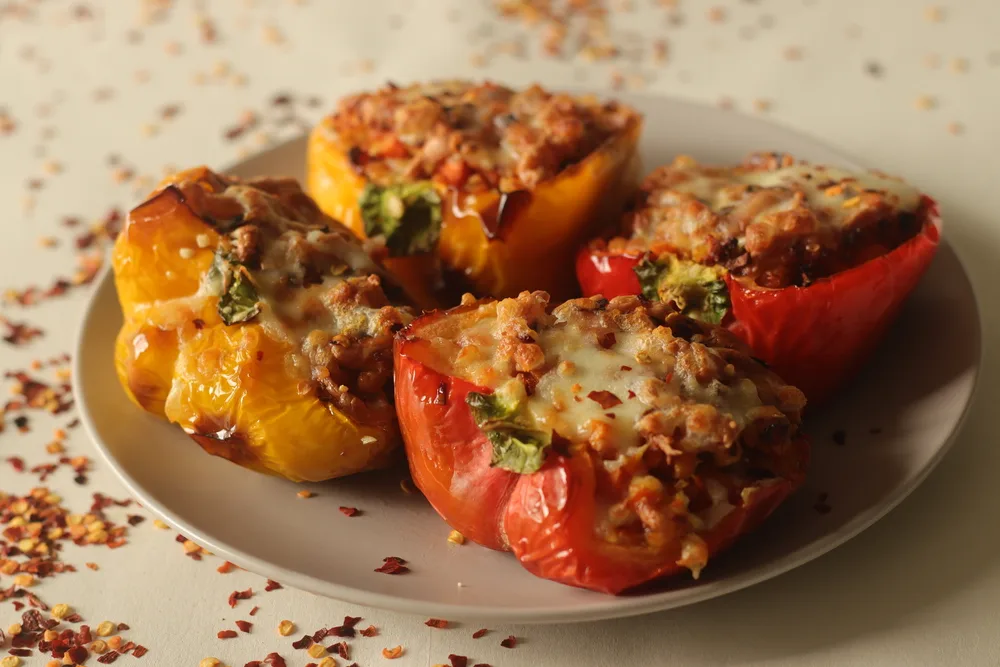 Stuffed bell peppers. Made by air frying the Bell peppers stuffed with a spicy mixture of sauteed cottage cheese and carrots, sprinkled with mozzarella cheese on top. Shot on white background.