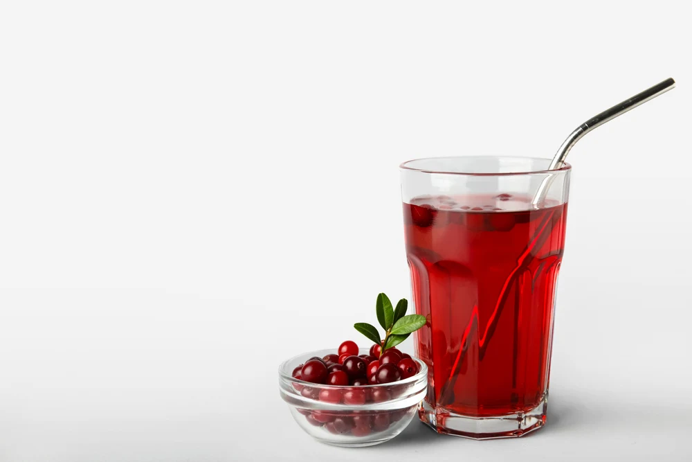 Glass with healthy cranberry juice on light background