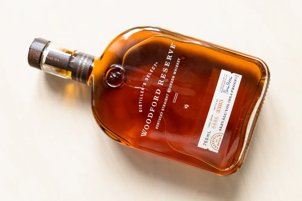 Top view of lying bottle with Woodford Reserve straight bourbon whiskey on light table. Making fine bourbon began on the site Woodford Reserve Distillery in 1812