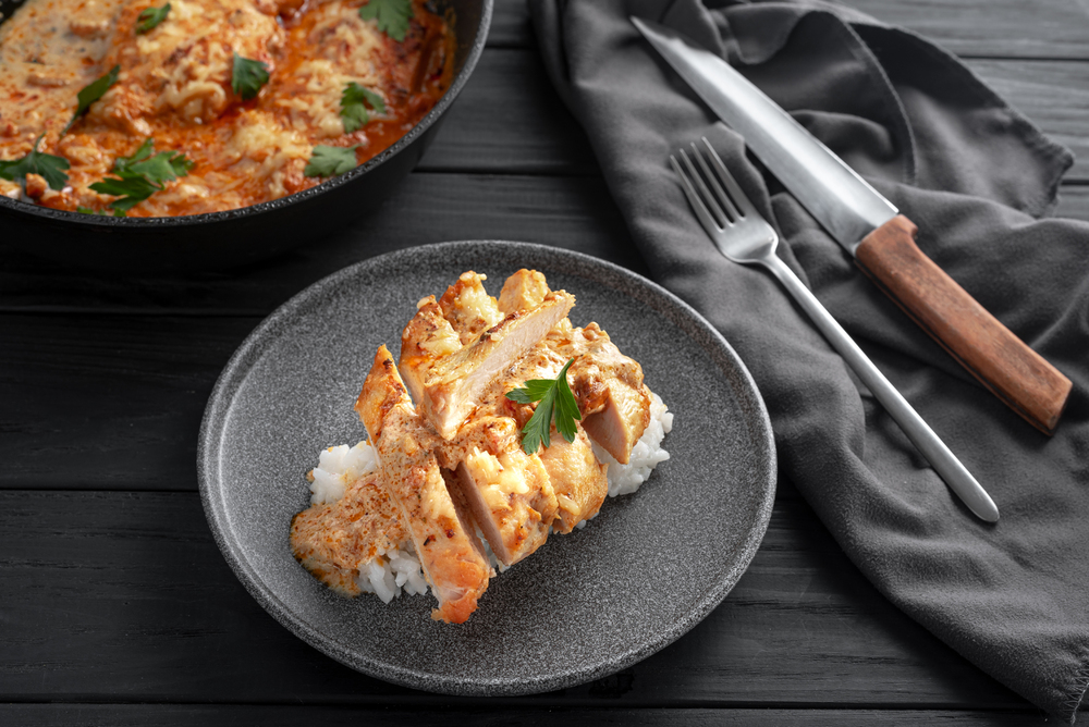 Chicken a la king fillet in cream sauce sliced into pieces on a gray plate.