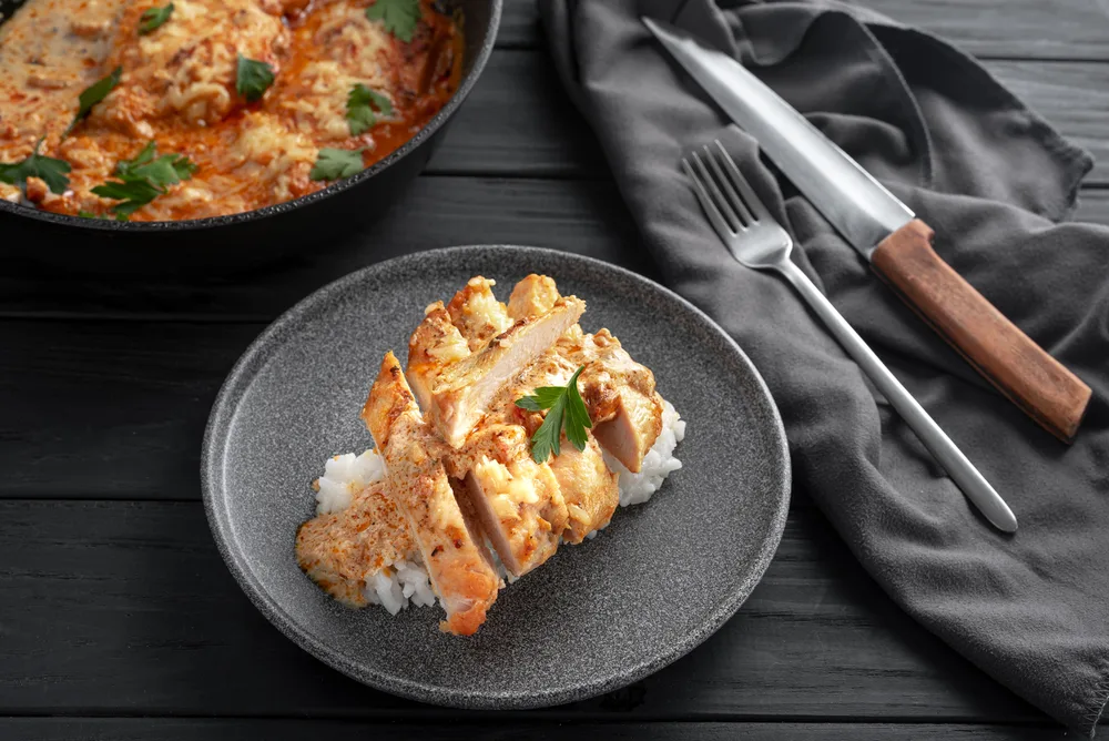 Chicken a la king fillet in cream sauce sliced into pieces on a gray plate.