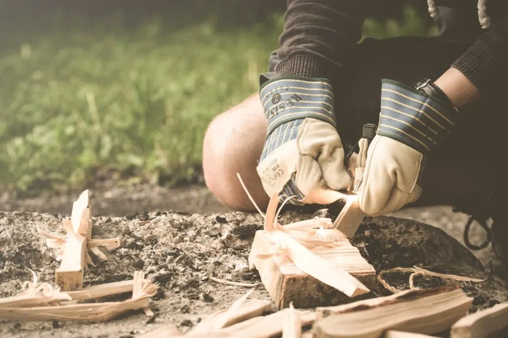 A person making fire from wood and a fire starter one of the key outdoor survival essentials