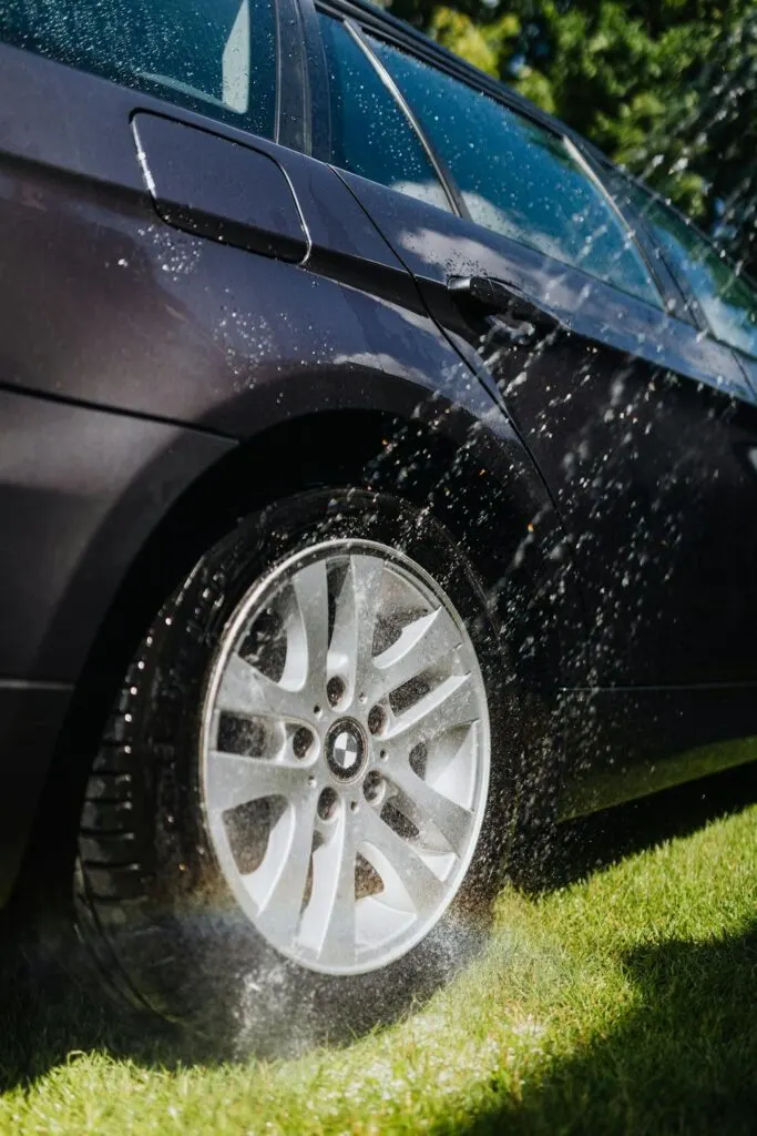A person rinsing off their tires after cleaning their car