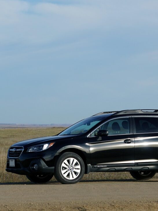 A black Subaru Forester, one of the best safe cars, is parked in front of a field