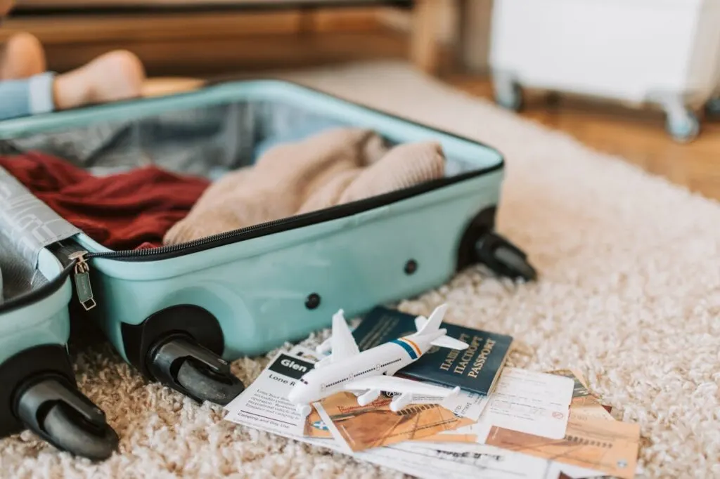 A packed suitcase on a bed along with a [passport and airline tickets