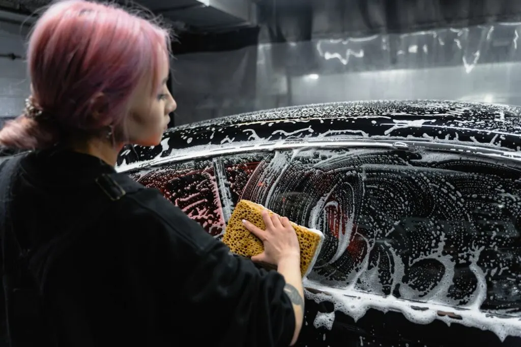 A woman washing a car as part of the auto detailing process