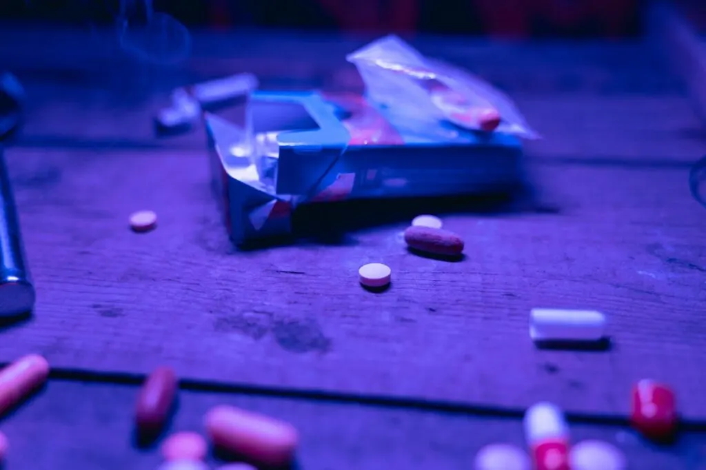 An empty cigarette pack on a table with various types of pills scattered around it illustrating the importance of choosing the right detox program for your addiction