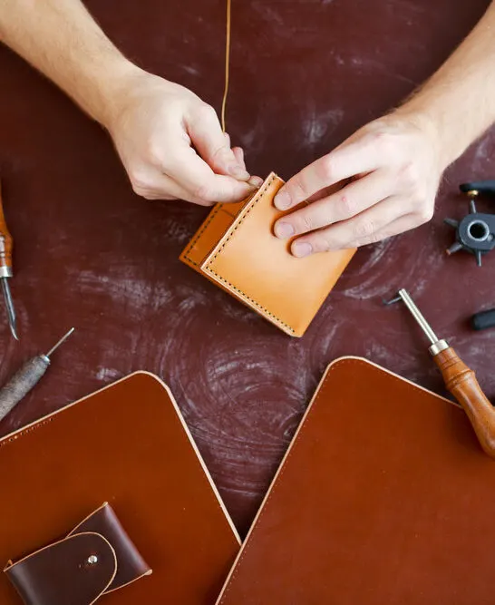 Human hands using handtool while producing leather item