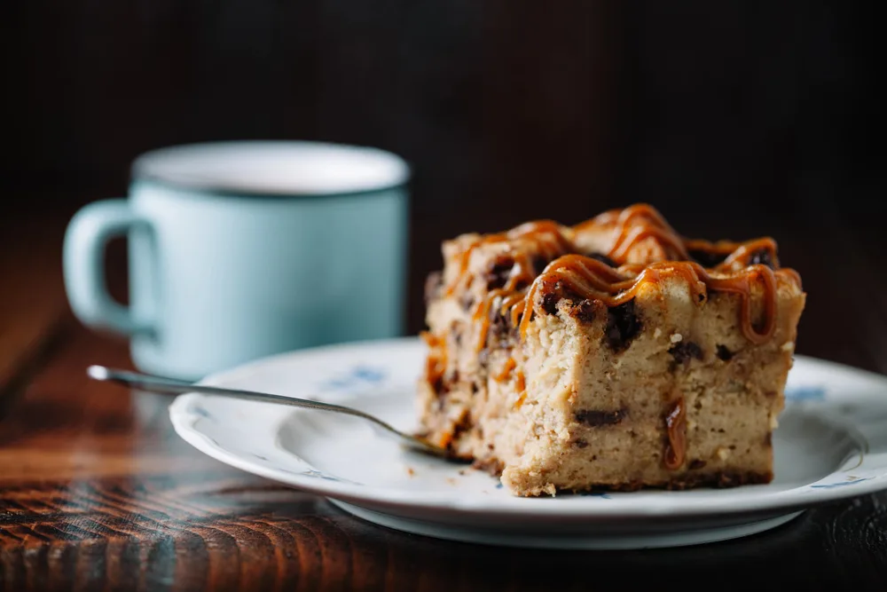 Bread pudding with caramel sauce served with a cup of hot cocoa — Stock Photo, Image
