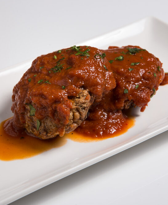Closeup of a serving dish of Salisbury steak with tomato sauce