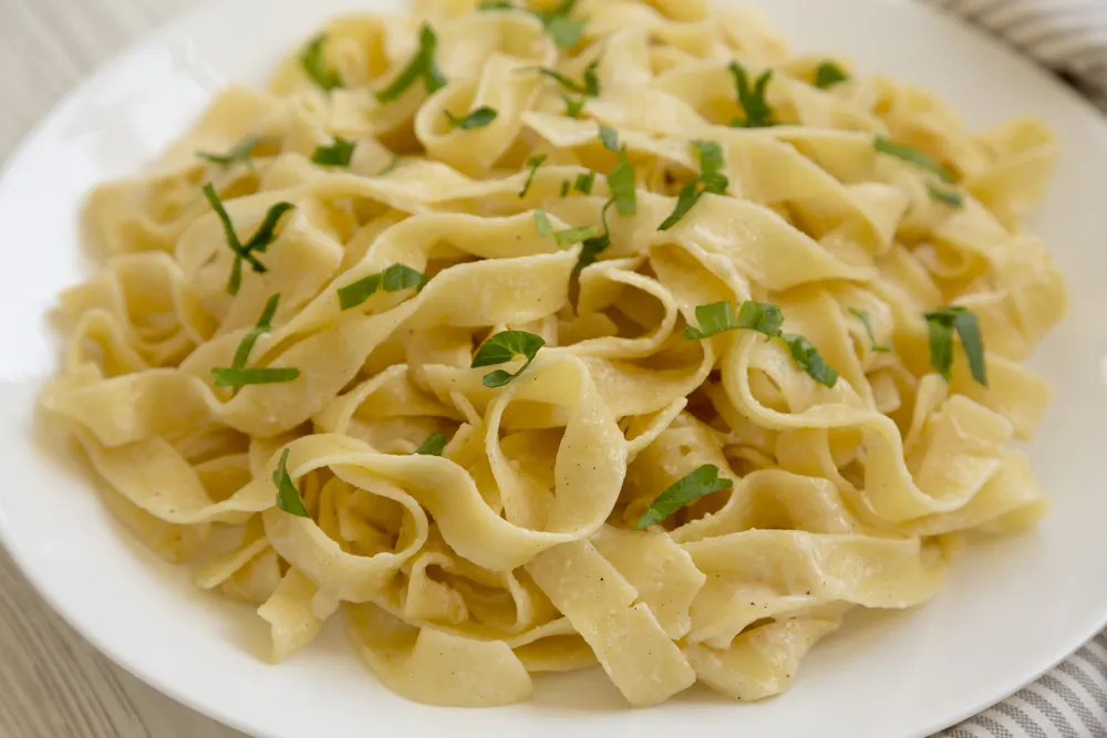 Uncooked brown pasta tagliatelle with chestnuts on a wooden