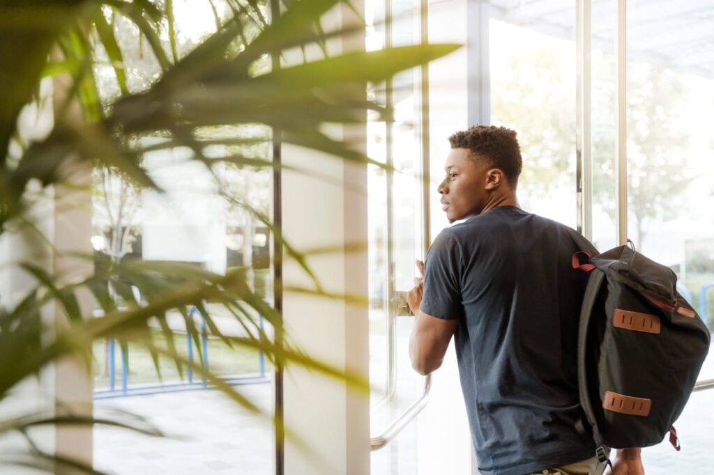 A college student with a backpack entering a building