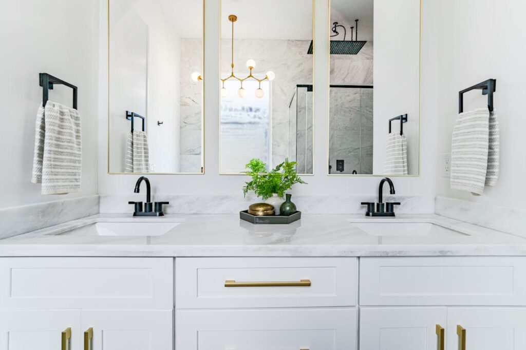 A white vanity with marble top and black handles as part of a bathroom upgrade