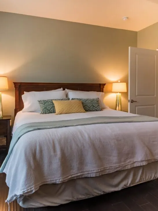 A made up bed in a bedroom with pillows and a comforter. Choosing the best mattress firmness directly impacts the quality of sleep.