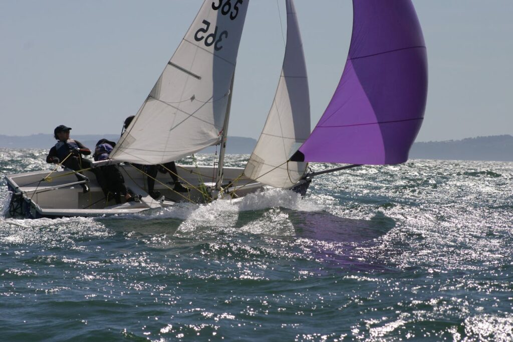 Two people boating in the ocean setting their sail