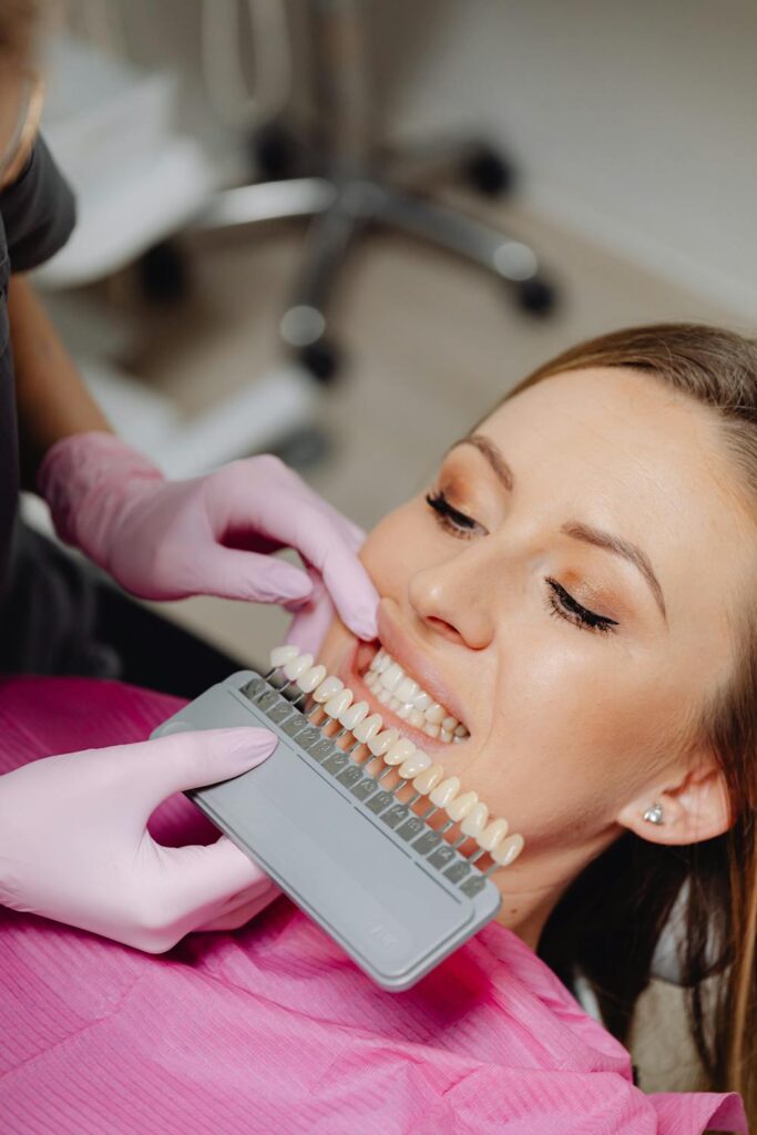 A dentist trying to match a crown to the same color in a woman's mouth in order to avoid a common cosmetic dentistry mistake