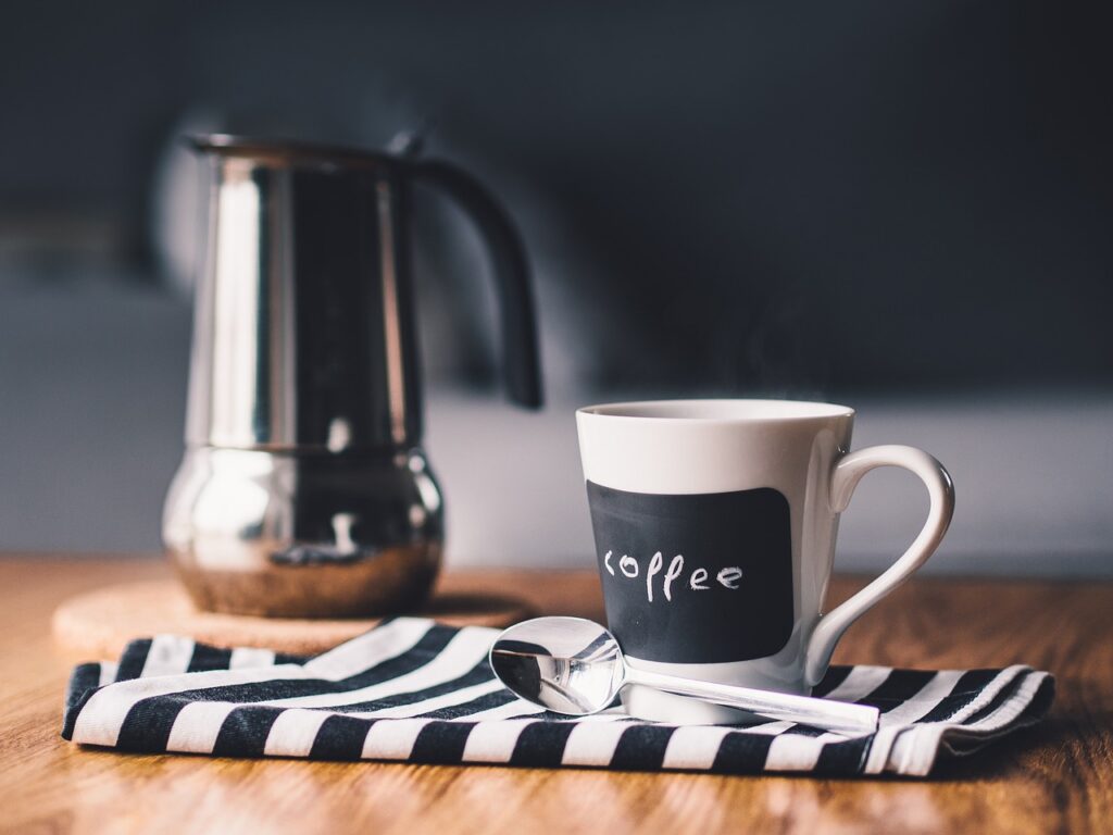 A pour over coffee maker and a coffee cup on a wood = table