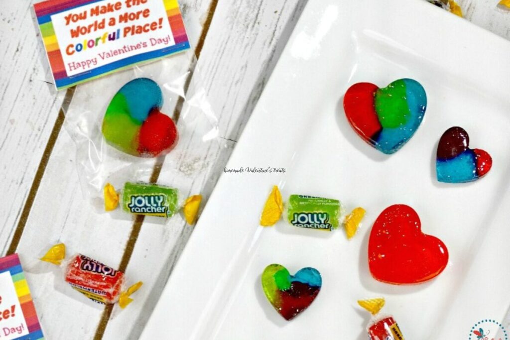 Colorful Rainbow Candy Hearts on a white plate with printable treat bag topper next to them.