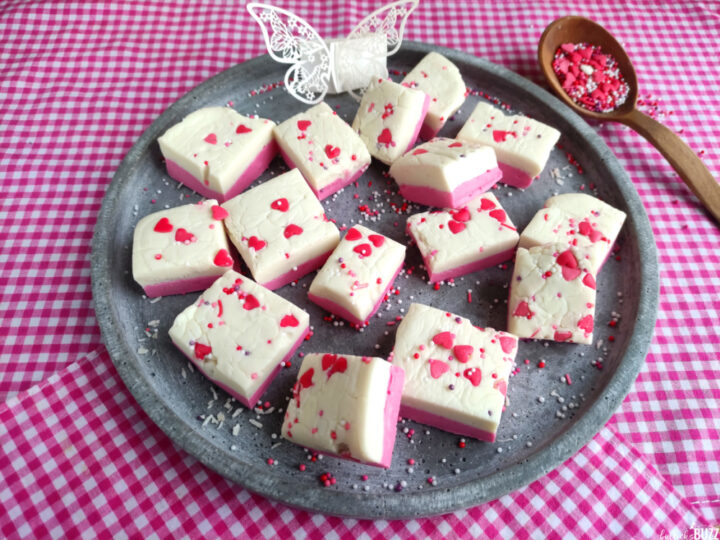 Pink and White No-Bake Fudge topped with candy hearts sitting on a grey plate. Another of our favorite Homemade Valentine's Treats