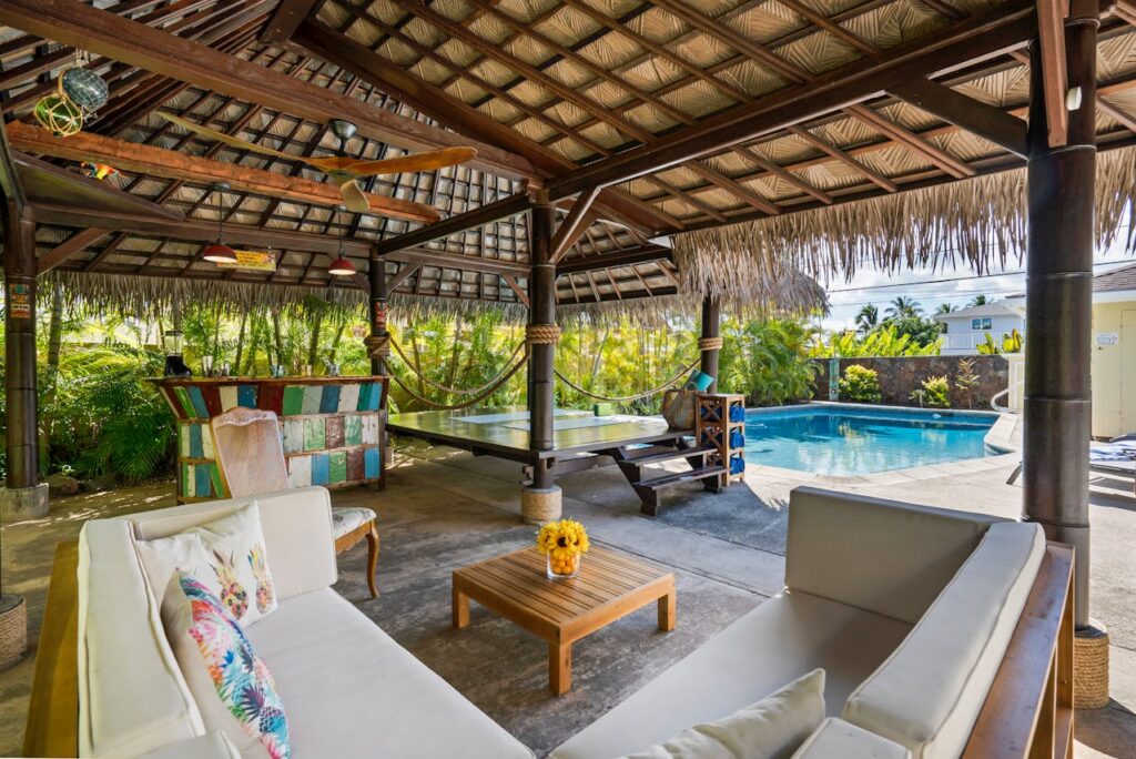 A beautiful patio by a pool with couches, an outdoor kitchen and more