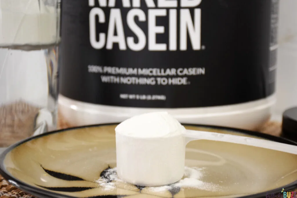 A large scoop of casein on a plate in front of the container of Naked Casein