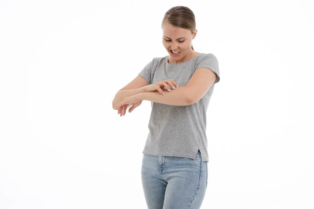 A woman scratching her arm. Itchy or tender areas can be one of the warning signs of skin caner