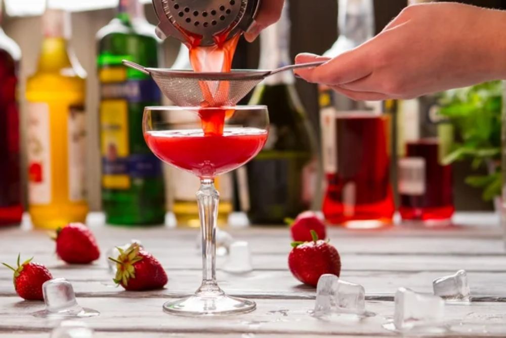 Red drink pours through sieve. — Photo
