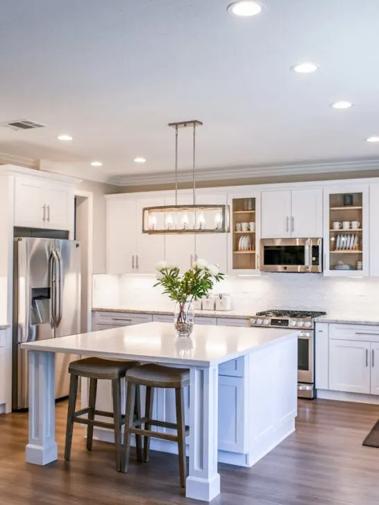 A white modern kitchen with a pretty box light. Changing lighting fixtures is a simple way to refresh your home on a budget.