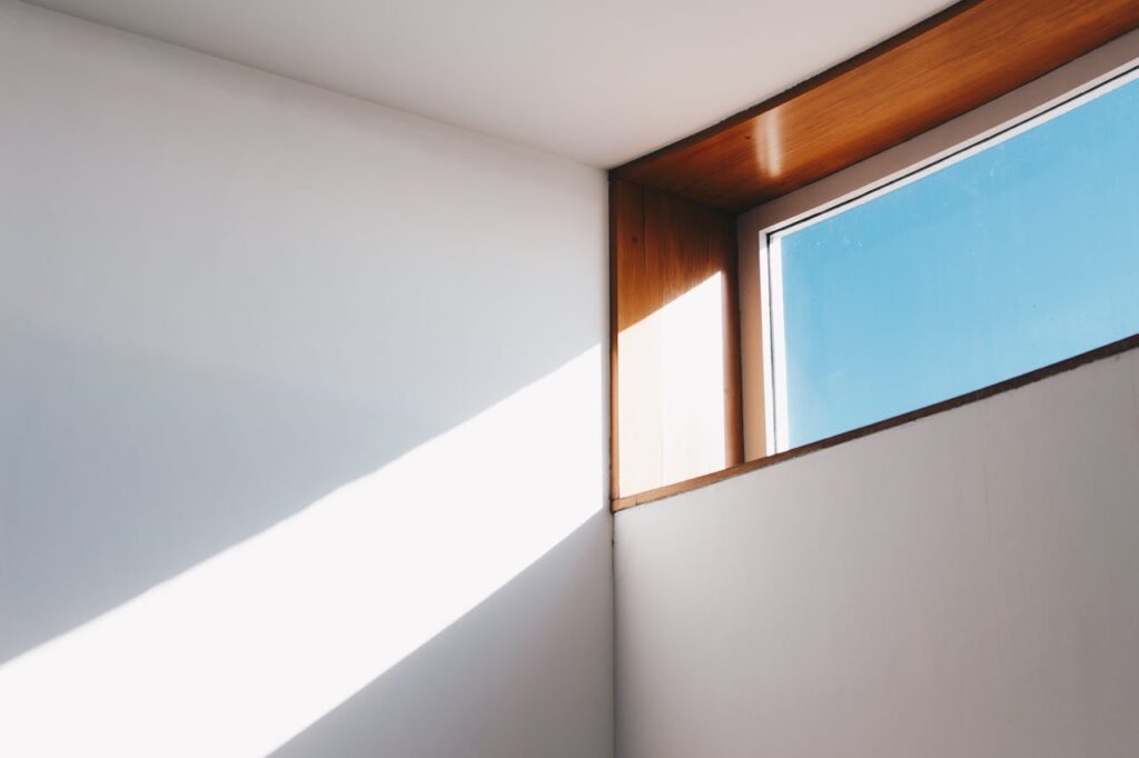 A rectangular window near the ceiling letting the sun shine in on the wall.