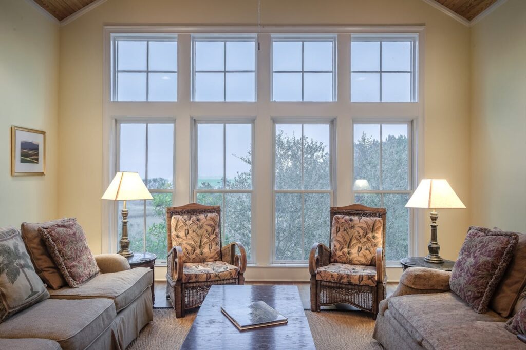 A large group of floor to ceiling windows in a living room  that will be expensive when it comes time to decide whether to go with window replacement or repair. 
