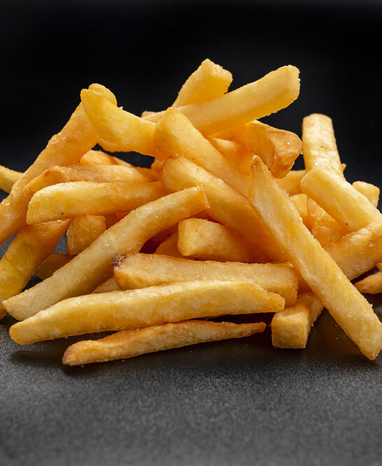 Pile of french fries over black background. Photo for the menu