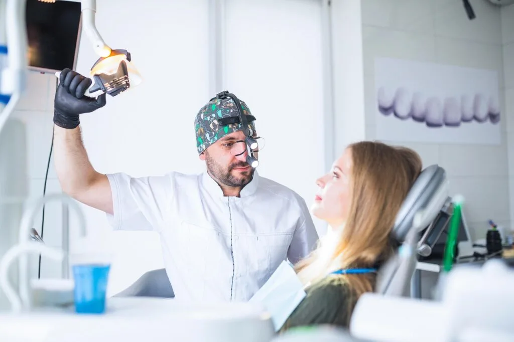 A girl in the dentist chair while he adjusts the light for an exam. There are many reasons why you shouldn't skip your dental appointments, oral health being the biggest.
