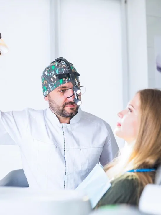 A girl in the dentist chair while he adjusts the light for an exam. There are many reasons why you shouldn't skip your dental appointments, oral health being the biggest.