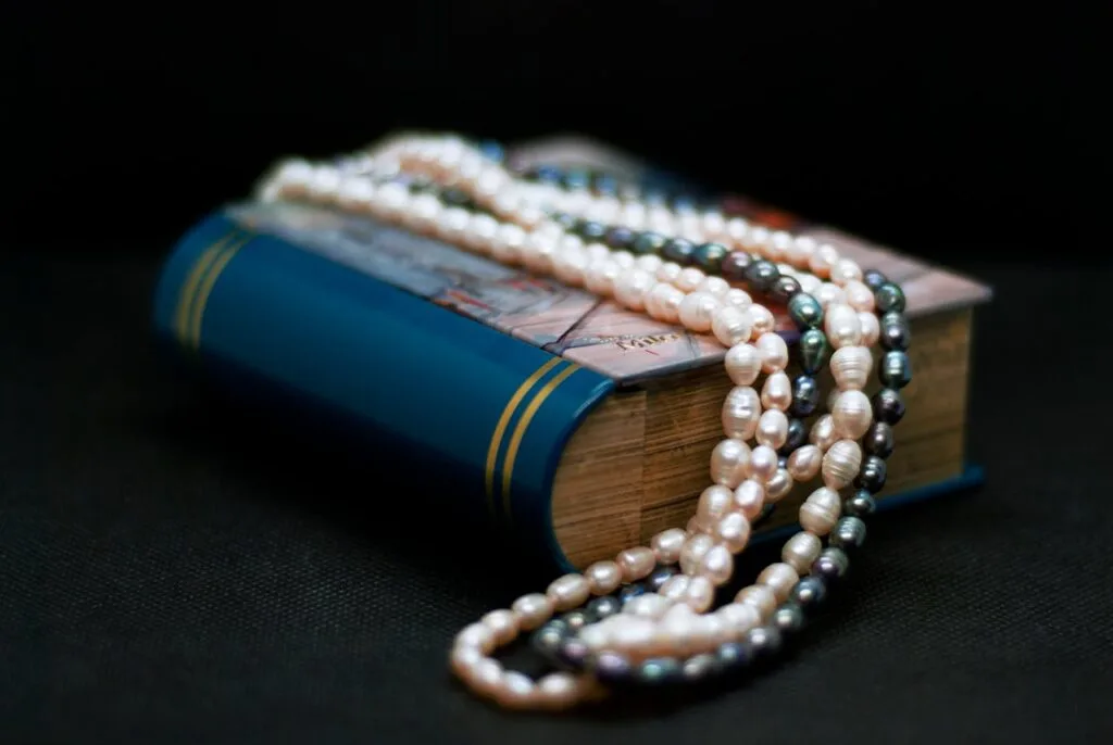 A strand of black pearls and white pearls draped over a book