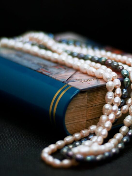 A strand of black pearls and white pearls draped over a book