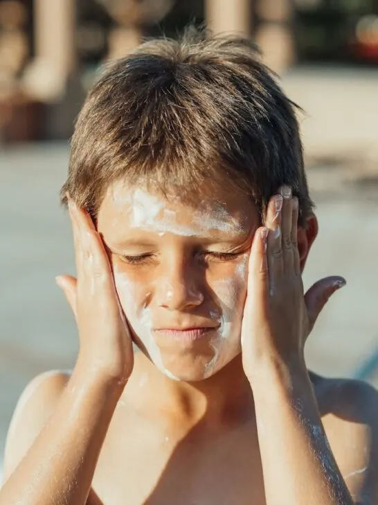 A child applying sunscreen to his face after learning how to choose the best sunscreen for your skin type