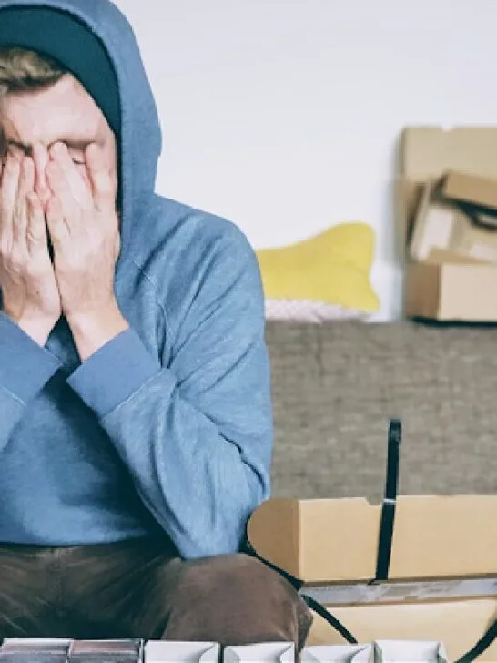 A man sitting down holding his head in his hands while considering hiring the best Title IX lawyer