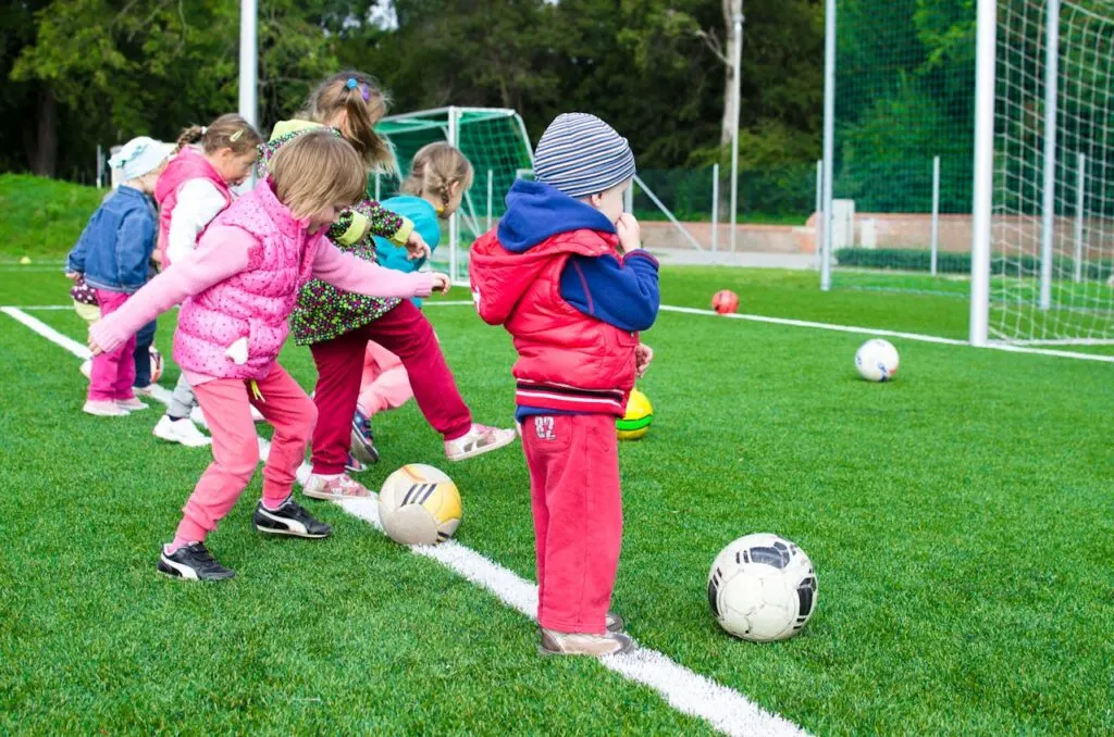 Little kids kicking soccer balls into the goals