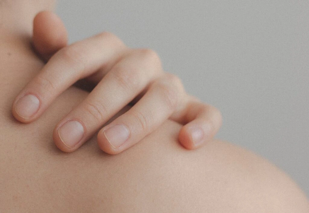 Close up of a hand on a person's shoulder with beautiful healthy skin from following healthy skin care tips